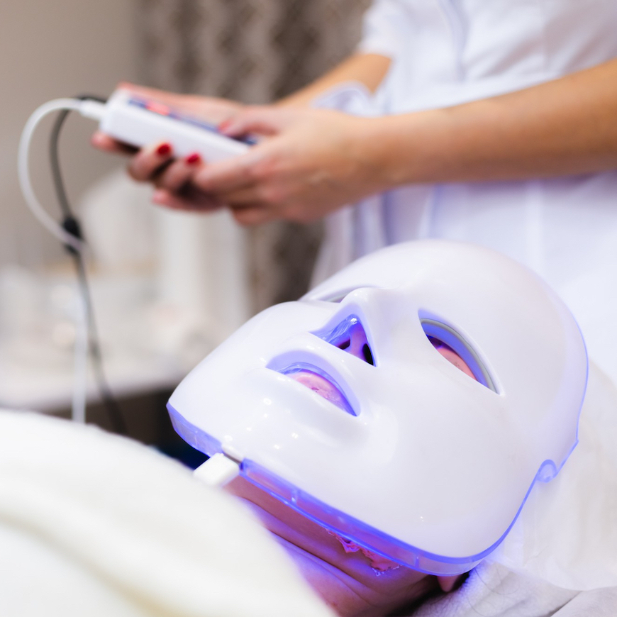 At home skincare devices Woman using LED light therapy mask at home